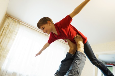 The boy depicts a plane with arms outstretched, supported on his fathers legs. Bottom viewの写真素材