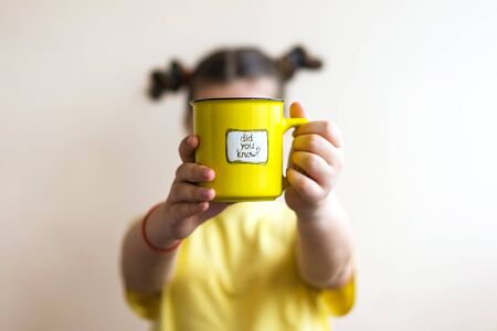 A girl in a yellow T-shirt with a yellow ring in her hand, on which was written Did you know. Interesting factの写真素材