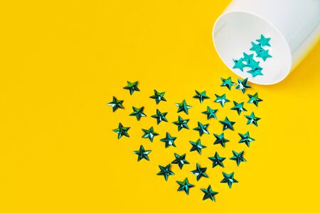 Creative festive white glass and sky blue heart from stars on a yellow background. Flat lay.の写真素材