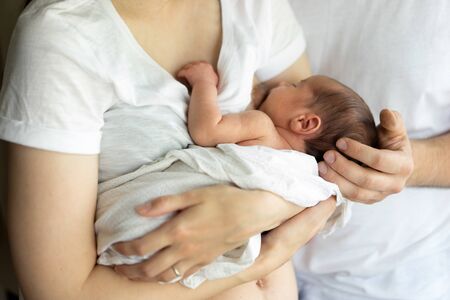 Father and mother with a newborn son. New young multi-generation family. Breast-feeding
