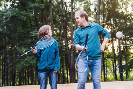 Father teaches son to play badminton in the park. Weekend for two. Parenting conceptの写真素材