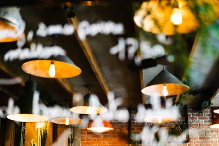 Blurred reflection of the ceiling of a cafe with beautiful lamps in the mirror with a written menu on glass. Out of focusの写真素材