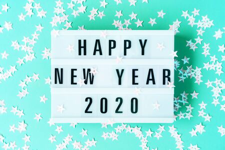Glowing neon light box on the mint green background with the inscription Happy New Year 2020. Trendy...