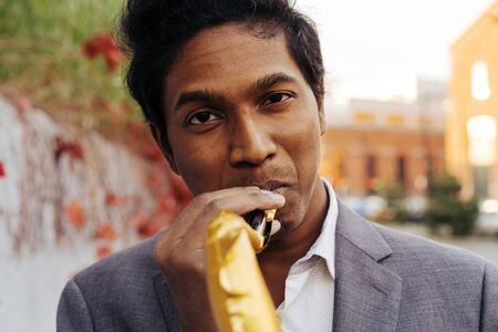 Funny handsome Indian man in a white shirt and a business suit with a golden color inflatable tube...