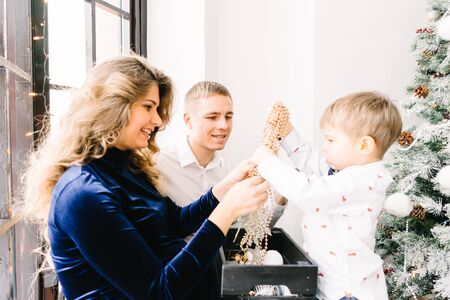 The little boy with his parents near a Christmas tree. Merry Christmas and happy New year concept. Happy family at homeの写真素材