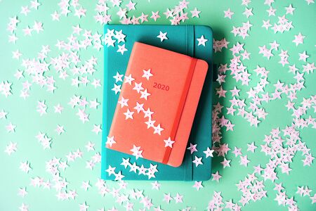 Orange diary for 2020 with artificial leather cover on a mint background shiny stars confetti. New...