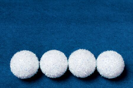 Four white fluffy Christmas snowball stars on a blue velvet paper background. Minimal New Year...