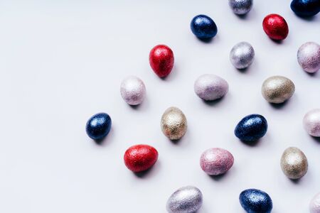 Colored painted pearl chicken and quail eggs of pink, silver, golden and blue color on a light blue pastel background. Minimalistic creative classic easter festive flat lay. Copyspace for textの写真素材