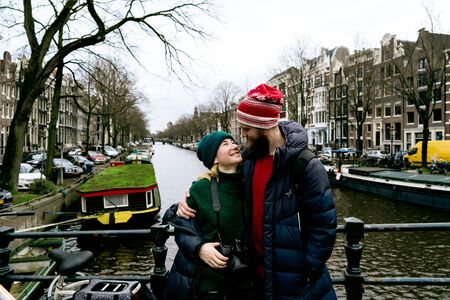 Loving couple man and woman having fun on the streets of Amsterdam in winter warm clothes. Husband embracing wife. Funny moments of life together. Valentine day conceptの写真素材