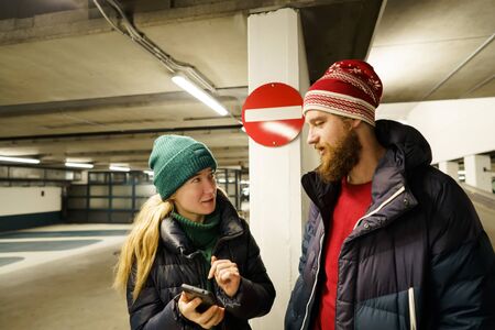 Loving couple A man and a woman lost in a sub-parking lot looking at the telephone navigation system...