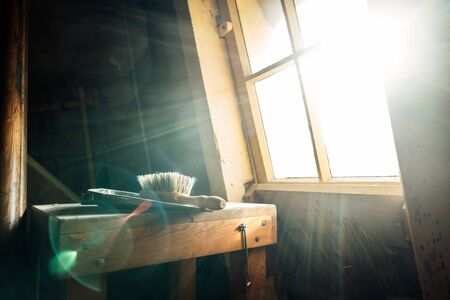 A wooden brush with natural bristles and a metal scoop lying on a wooden surface in an old Dutch...