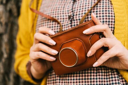 Woman with in the park with retro photo camera. Fashionable autumn clothes in orange mustard tonesの写真素材