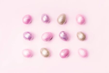 Colored painted pearl chicken and quail eggs of pink, silver, golden and blue color on a light blue...