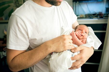 Father holds naked newborn son in his hands in a white diaper.の写真素材