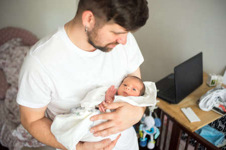 Father holds newborn son in his hands in a white diaper.の写真素材