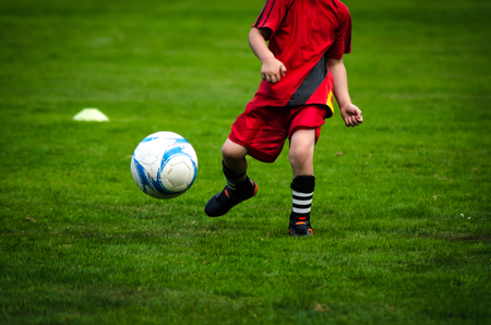 Picture of kids soccer training match with shallow depth of field. Focus on foreground meadowの写真素材
