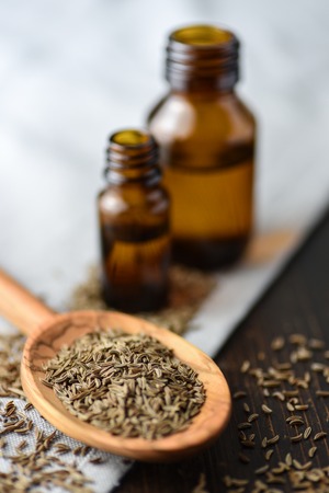caraway oil and seeds on wooden spoon and essential oilの写真素材