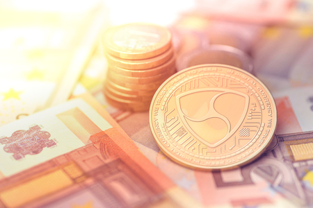 shiny golden NEM cryptocurrency coin on blurry background with euro moneyの写真素材