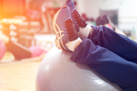 exercising with personal trainer on large stability ball in studio fitness back physiotherapyの写真素材