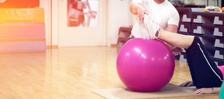 exercising with personal trainer on large stability ball in studio fitness back physiotherapyの写真素材