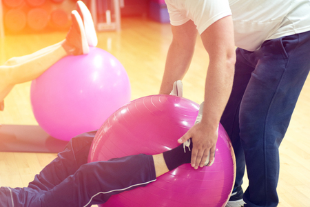exercising with personal trainer on large stability ball in studio fitness back physiotherapyの写真素材