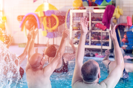 Group or young and senior people in aquarobic fitness swimming pool exercisingの写真素材