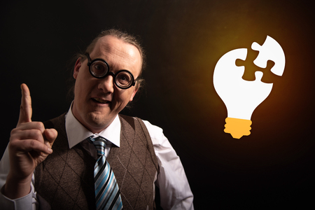Funny nerd or geek looking to light bulb having an ideaの写真素材