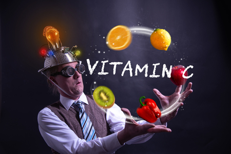 Funny nerd or geek juggles with fruits and vegetables vitamin cの写真素材