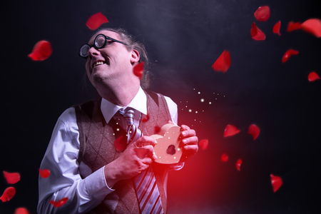 Crazy happy guy holding red heart gift box - present valentines day - love - with flying petals - rosesの写真素材