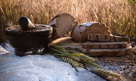 bread flour and corn on a old table with cornfield in the backgroundの写真素材