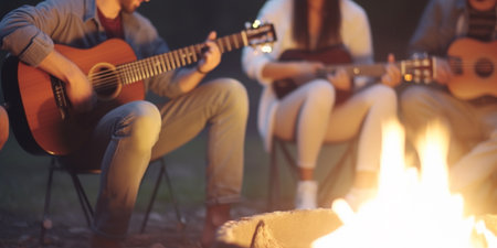 Group of friends enjoying a musical night by the campfireの素材