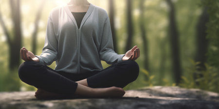 A woman finds inner peace while meditating in a cross-legged yoga poseの素材