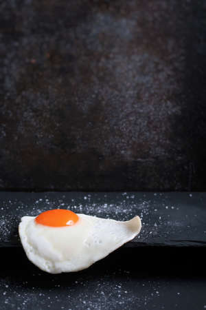 Fried egg and salt on black board.の写真素材