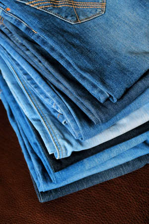 Blue jeans stacked on brown leather background.の写真素材