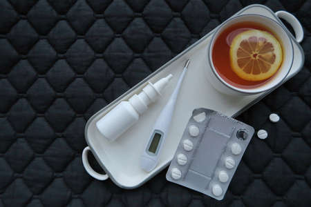 Cup of tea, bed, thermometer, nasal spray and paracetamol. First aid in winter season of cold and...