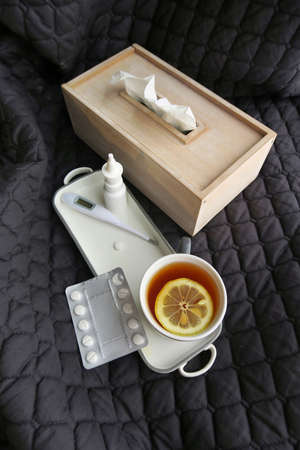 Cup of tea, bed, thermometer, nasal spray and paracetamol. First aid in winter season of cold and flu with fever.の写真素材