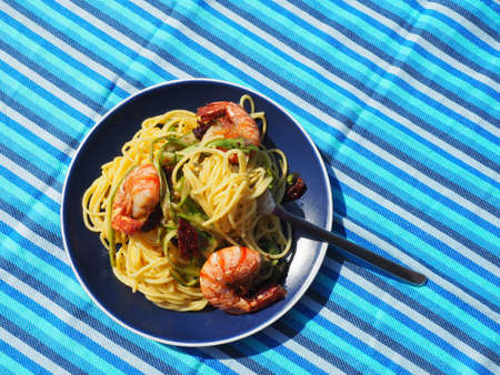 Spaghetti with shrimps on blue plate and blue tablecloth.の写真素材