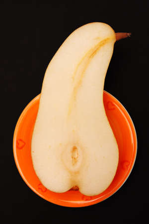 A half of pear on the orange plate.の写真素材