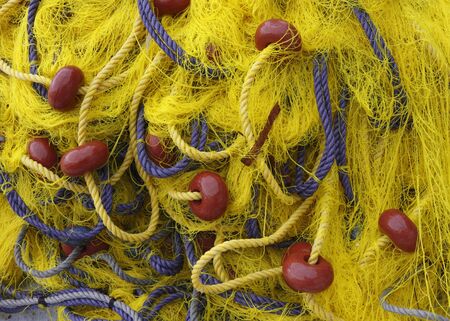 Yellow fishnet with blue ropes and red floats in the heap.の写真素材