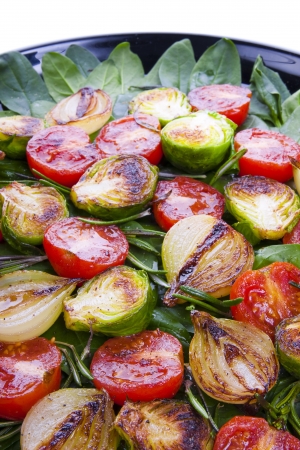 Roasted vegetables on leaves of green spinach  Photo close-up の写真素材