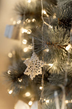 Snowflake hanging on christmas tree with blurred lights.の写真素材