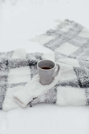 A cup of tea in winter is on a plaid in the snow.の写真素材