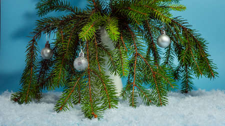 New Year's fir branches in the snow with toys in a vase on a hollow background in the snow.の写真素材