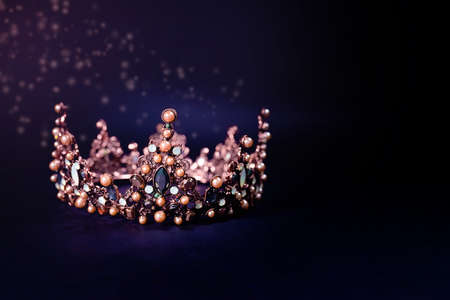 Beautiful golden queen crown on dark background in low key with glow, space for text.の写真素材