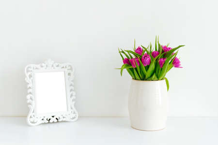 A bouquet of purple tulips in a white vase on a tableの写真素材