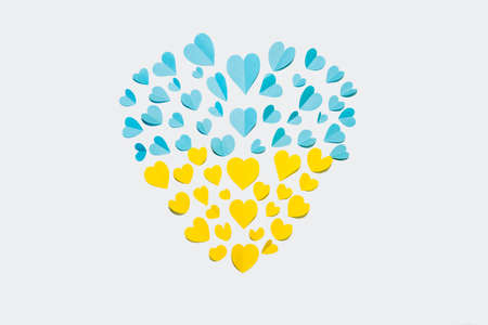 A lot of paper hearts in the shape of a big heart in the colors of the flag of Ukraine on a white...