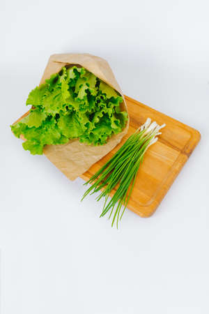 Lettuce leaves wrapped in kraft paper green onions lie on a cutting board. food concept.の写真素材