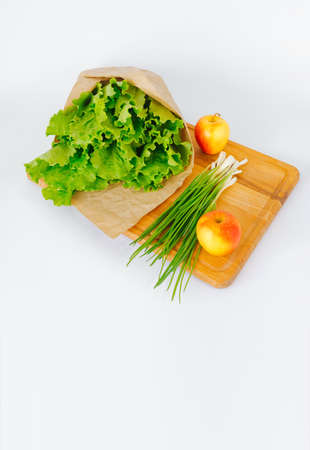 Lettuce leaves wrapped in kraft paper green onions lie on a cutting board. food concept.の写真素材