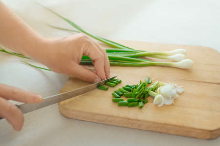 Male hands cutting green onions on a cutting board, home cooking.の写真素材