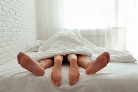 Pair of legs close-up under a coverletの写真素材